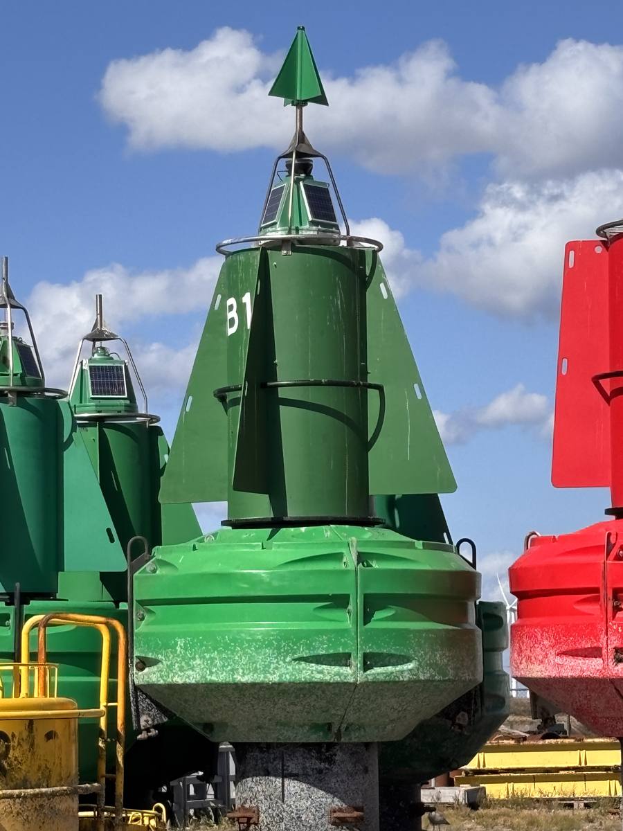 Groene kegelvormige laterale ton van stuurboord met groen kegelvormig topteken, opschrift B1, aan wal in een tonnenpark, rode ton rechts
